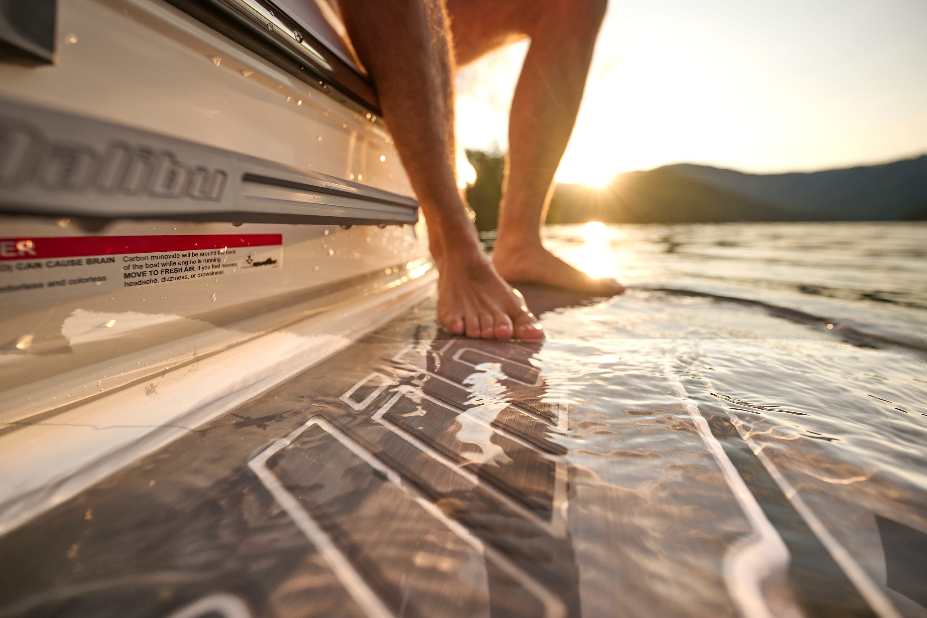 Bare feet on the swim platform of a Malibu 20 VTX at sunset