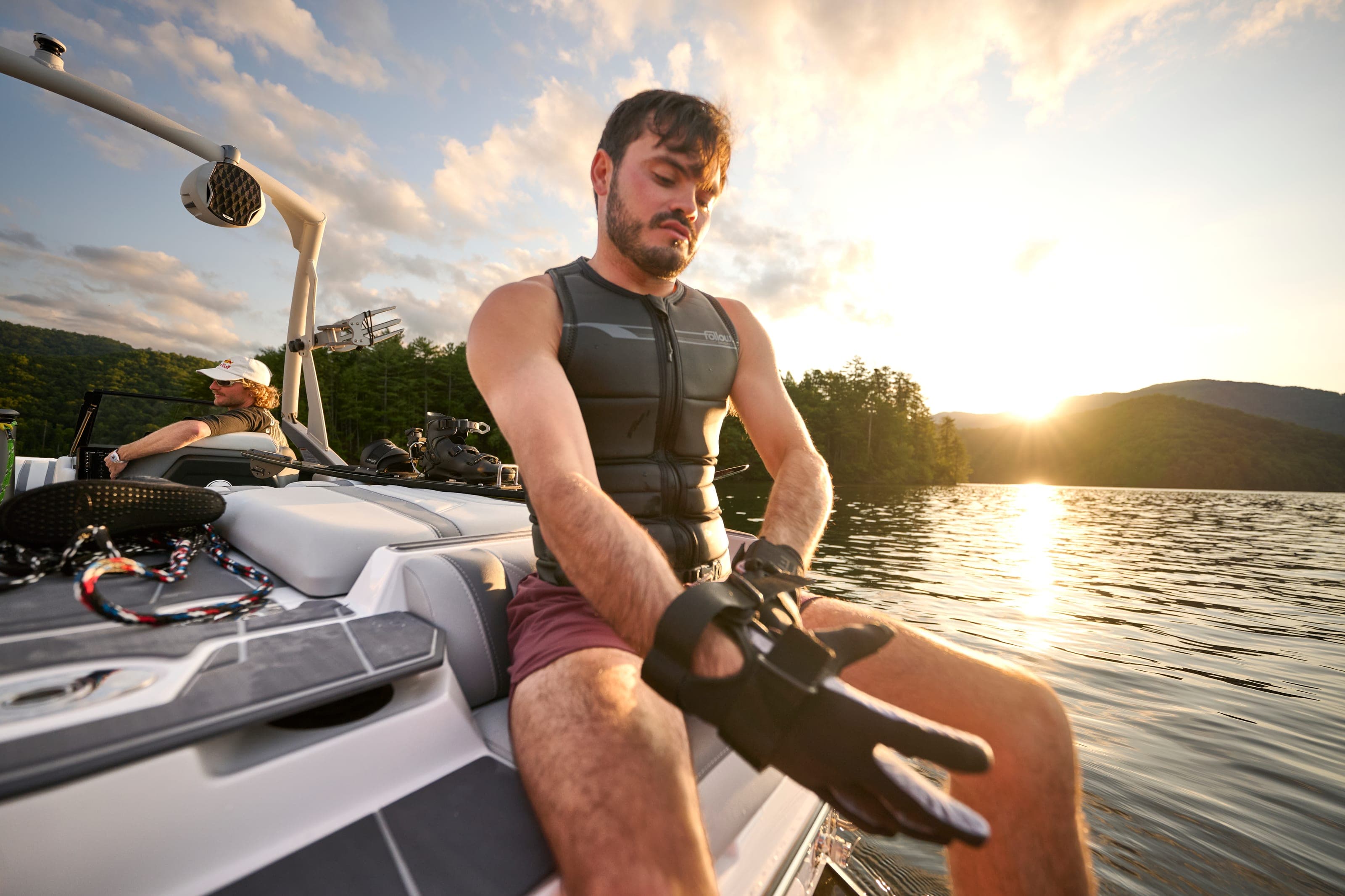A rider pulls on gloves aboard a Malibu 20 VTX at sunset