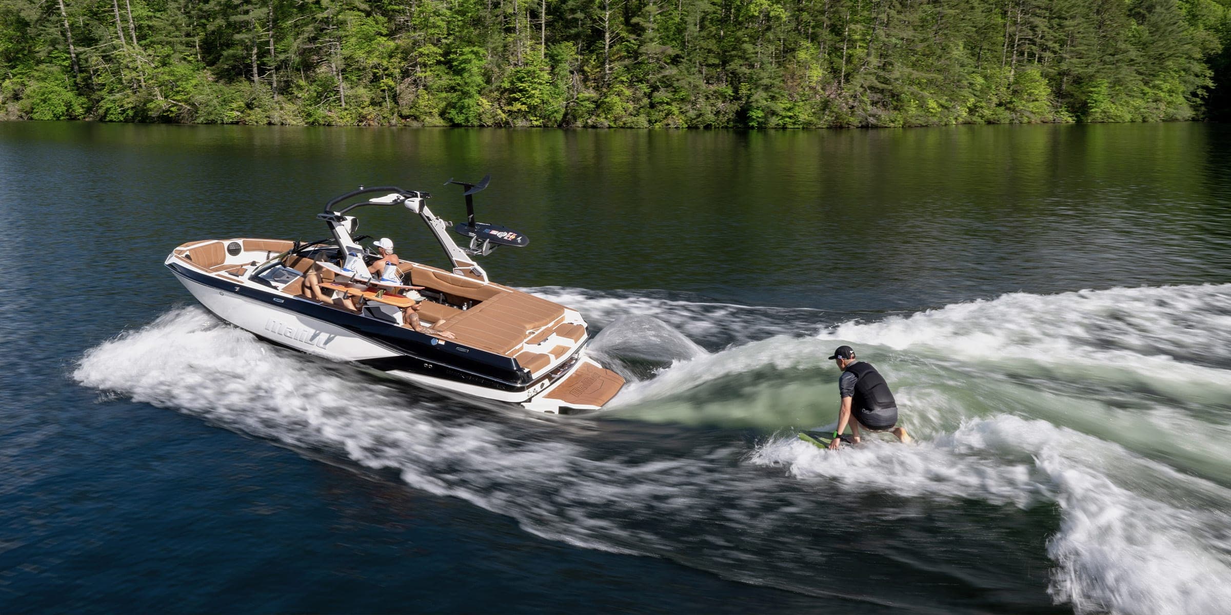 A Malibu 21 LX at speed with a surfer behind it
