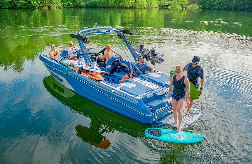 Riders stepping off the swim platform of a Malibu 22 MXZ