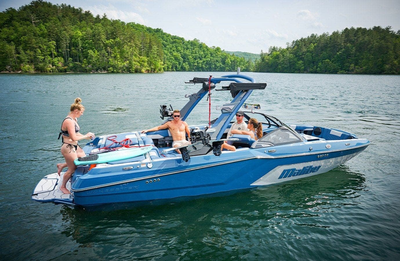 A Malibu 22 MXZ at rest on a lake, people aboard