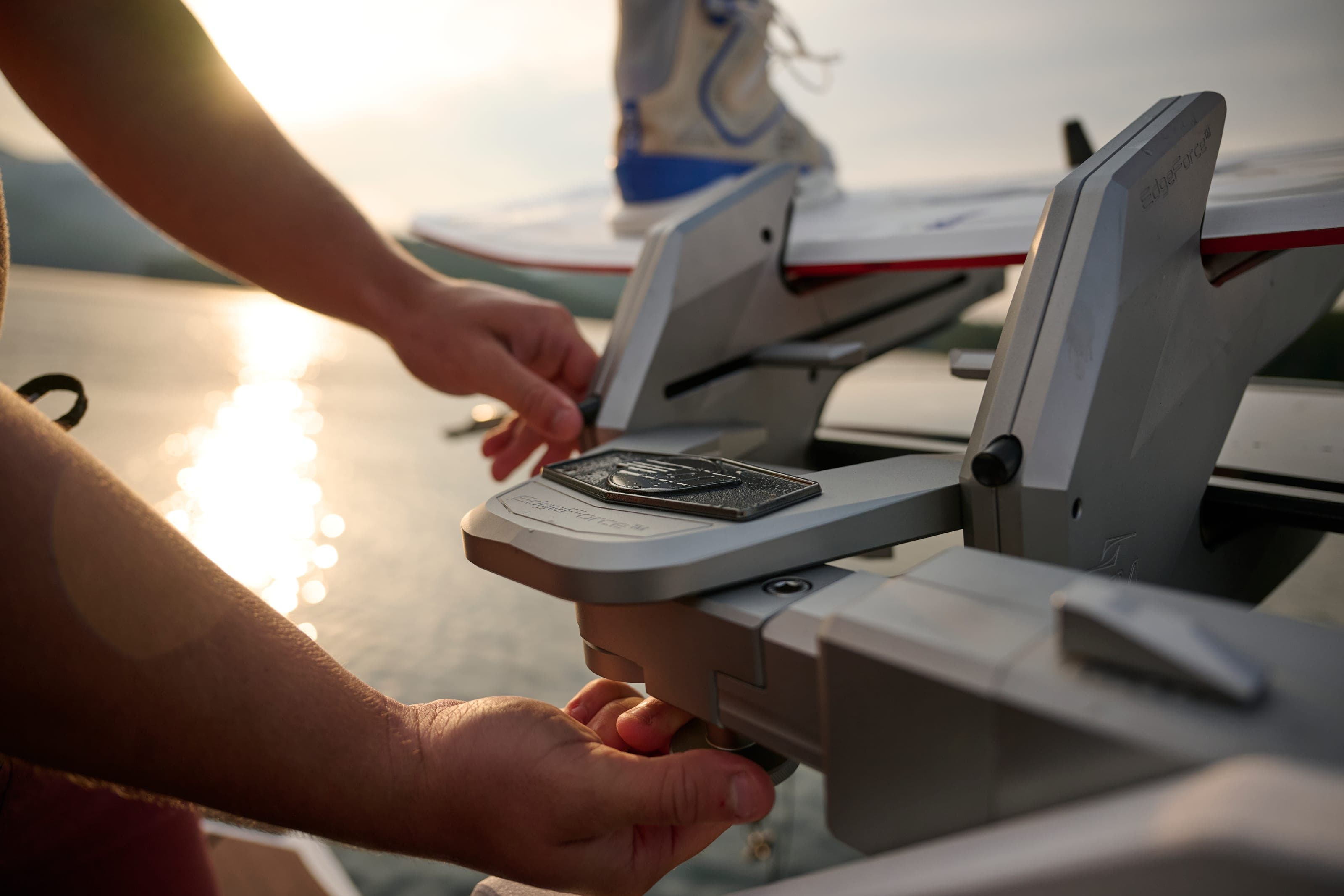 Hands at work on the stern hardware of a Malibu 23 LSV in the low sun