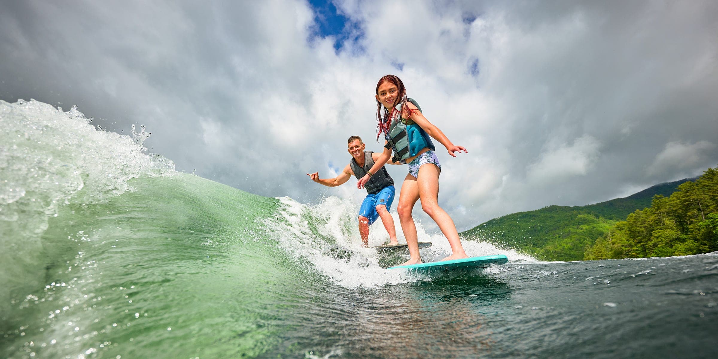 Two riders surfing one wave behind a Malibu 23 MXZ