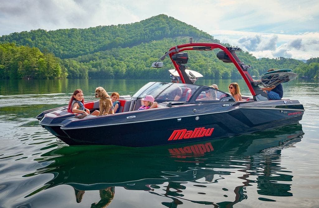 A Malibu 23 MXZ on a lake, family aboard