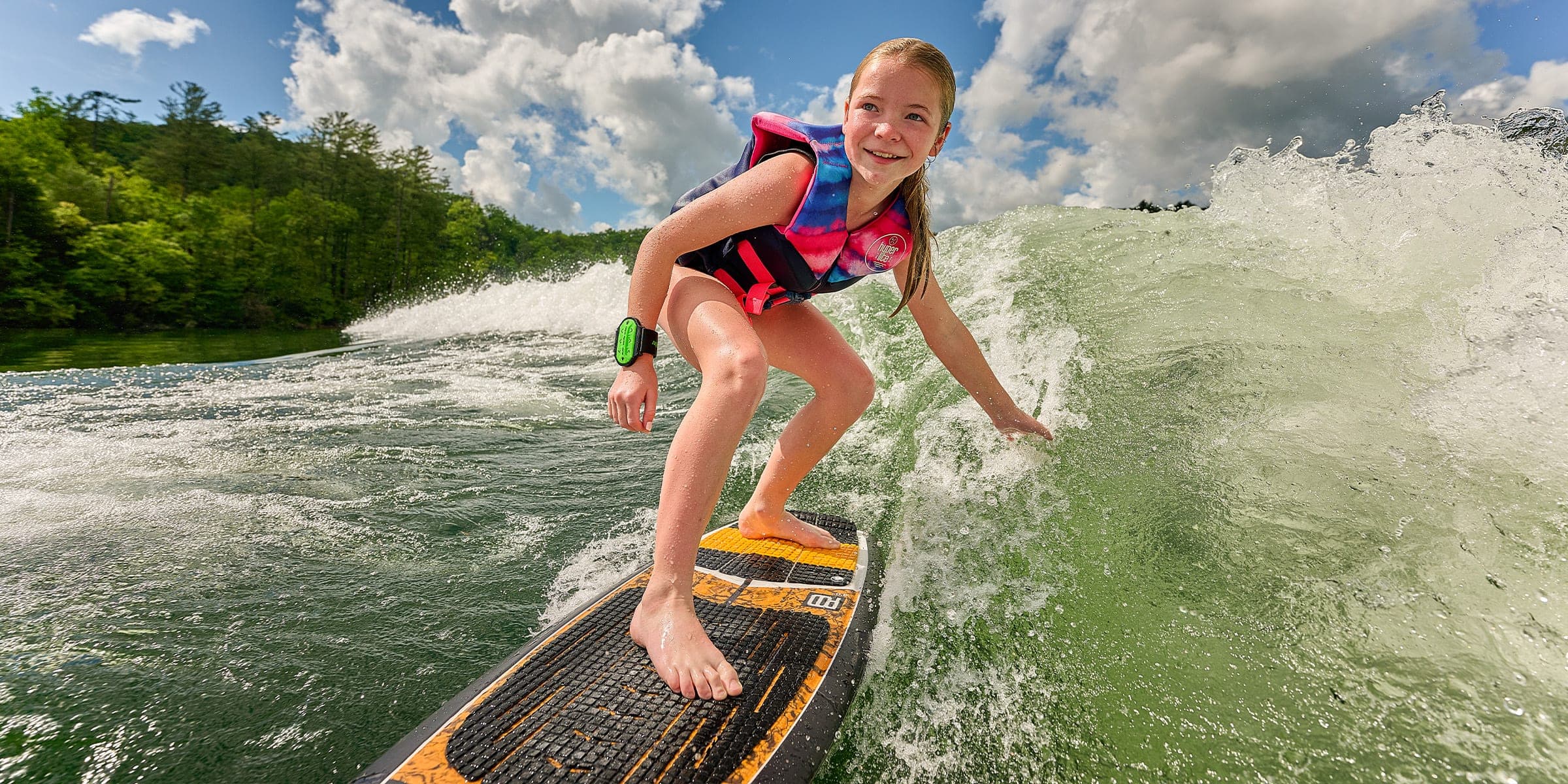 A girl wakesurfing behind a Malibu 24 MXZ
