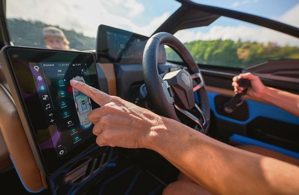 A hand on the command centre touchscreen of a Malibu 24 MXZ