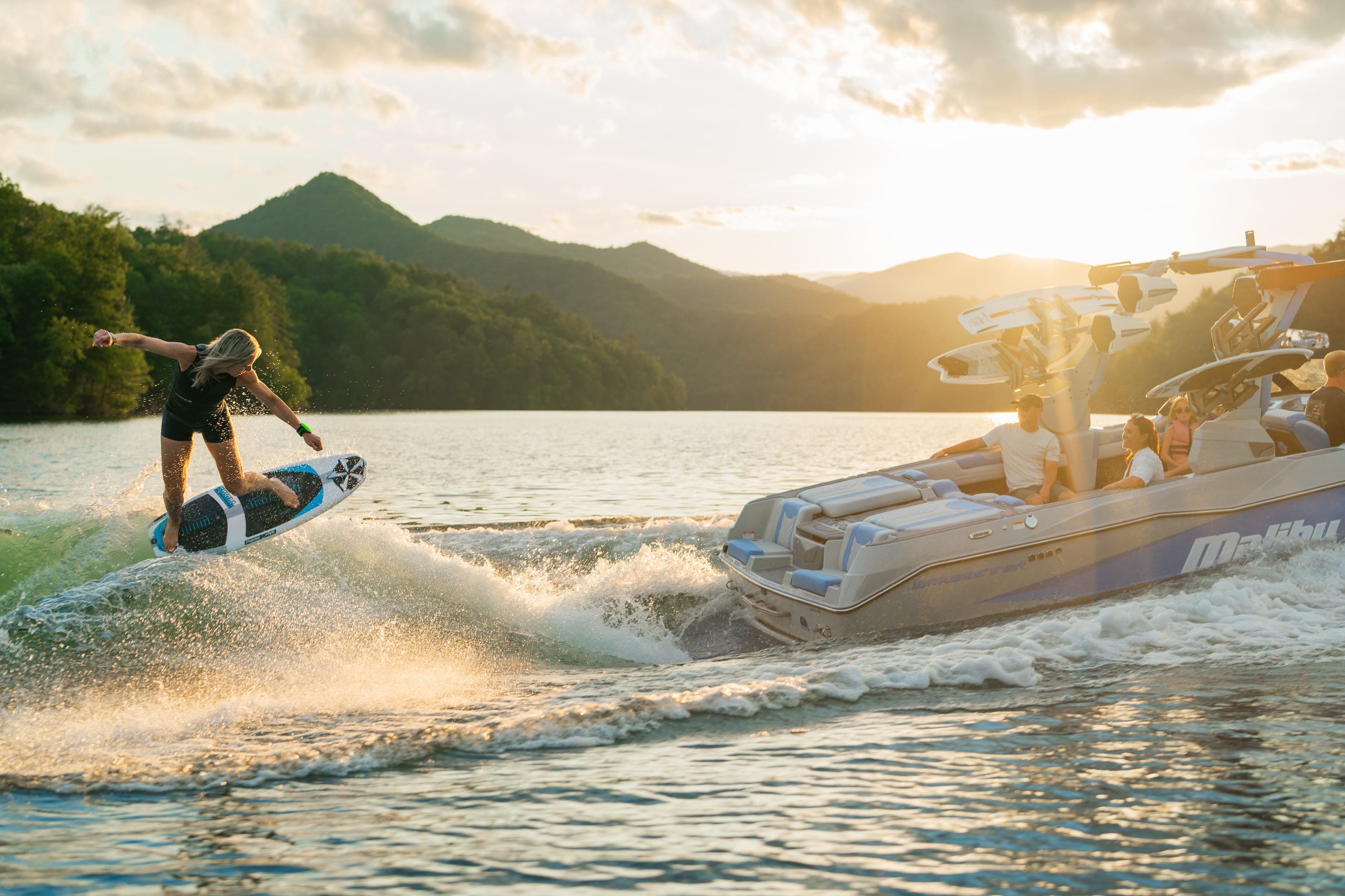 A rider surfs the wave behind a Malibu 25 LSV at sunset