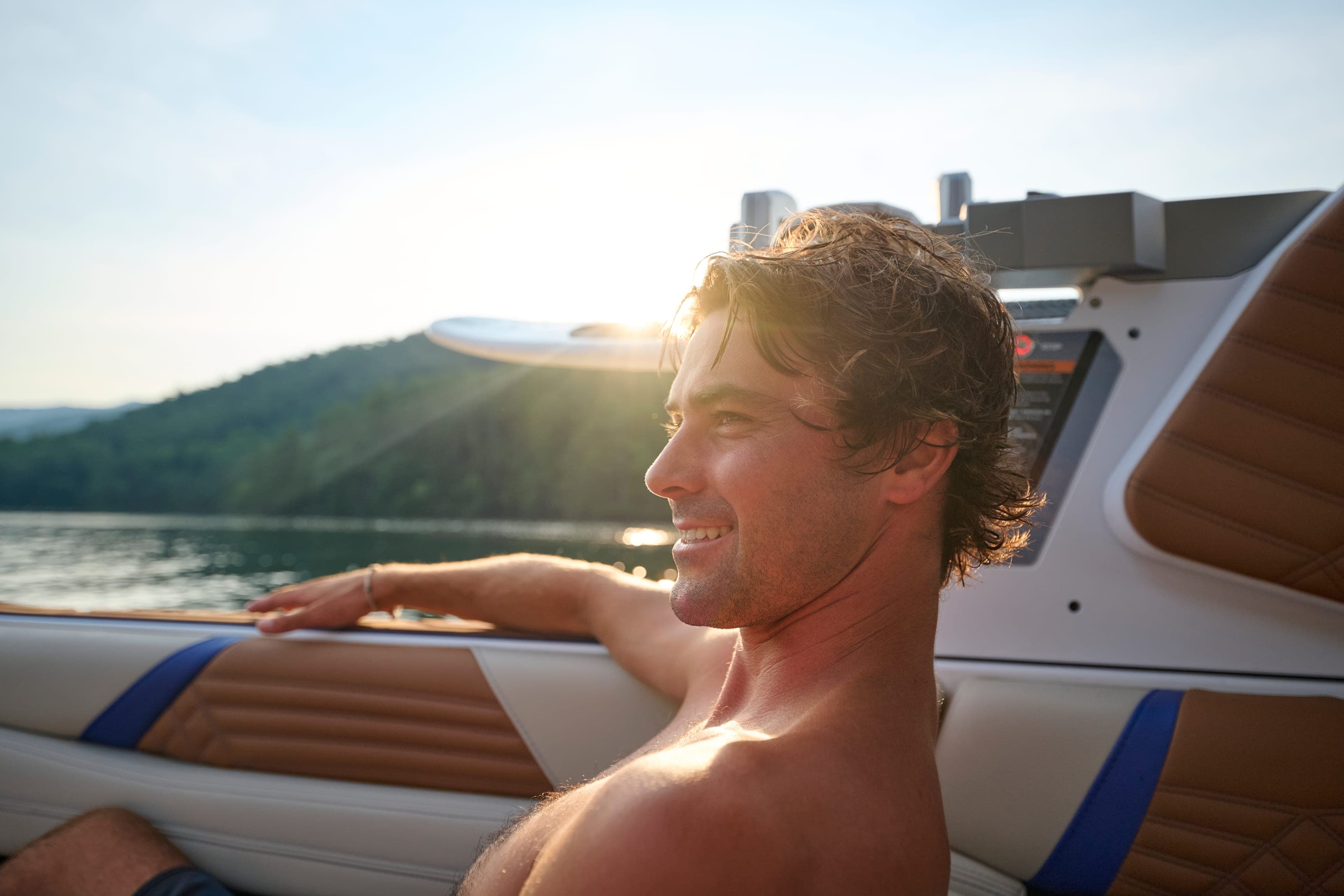 A man smiles in the low sun aboard a Malibu 26 LSV