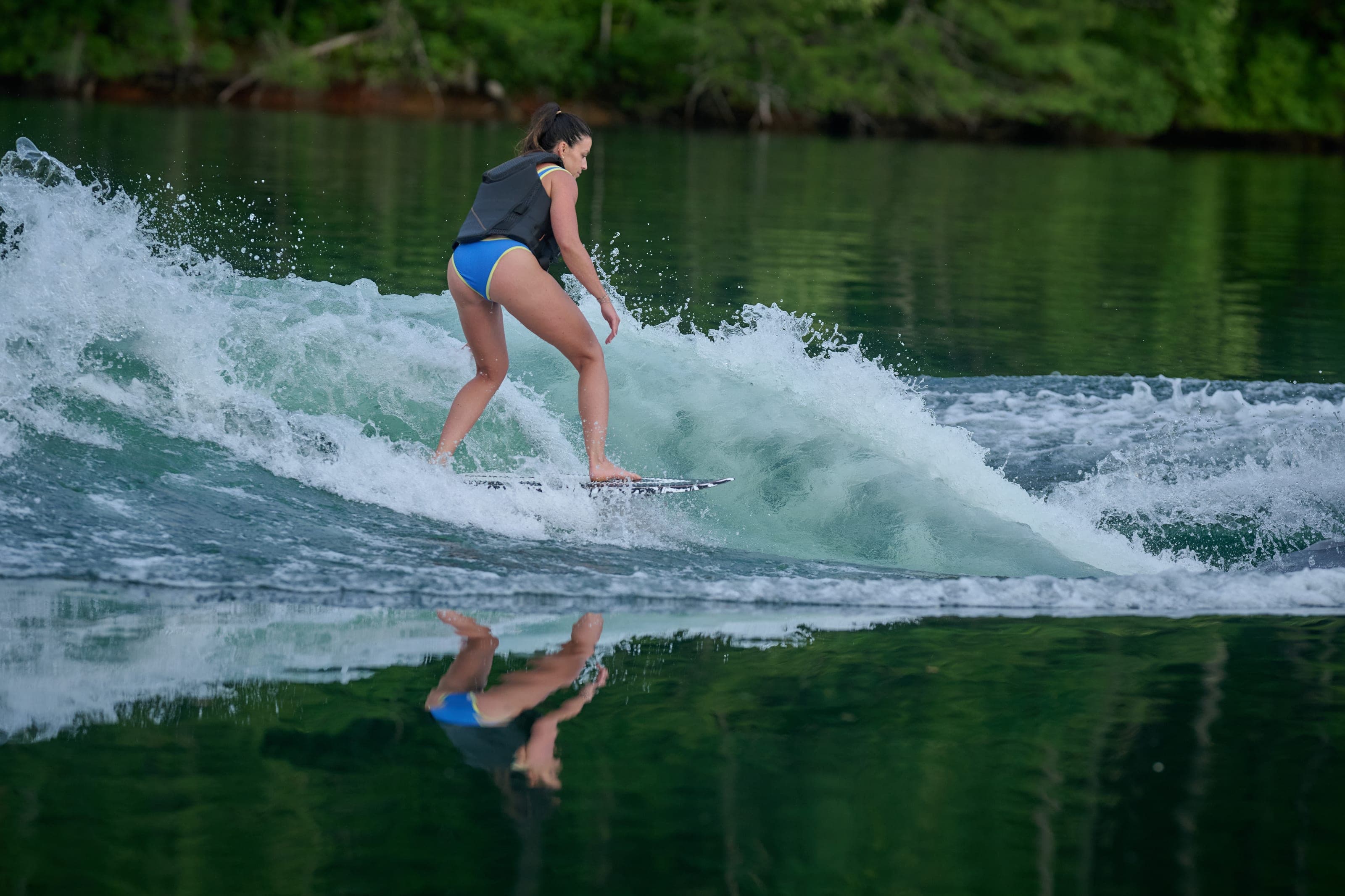 A woman surfs the wave behind an Axis T220