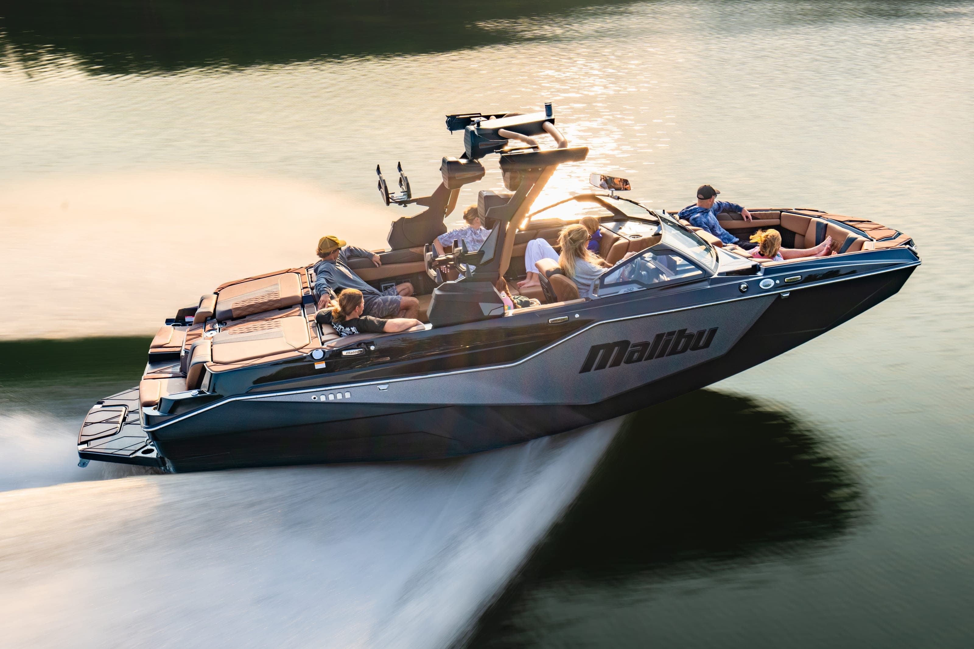 A Malibu M242 at speed in the low sun, people aboard