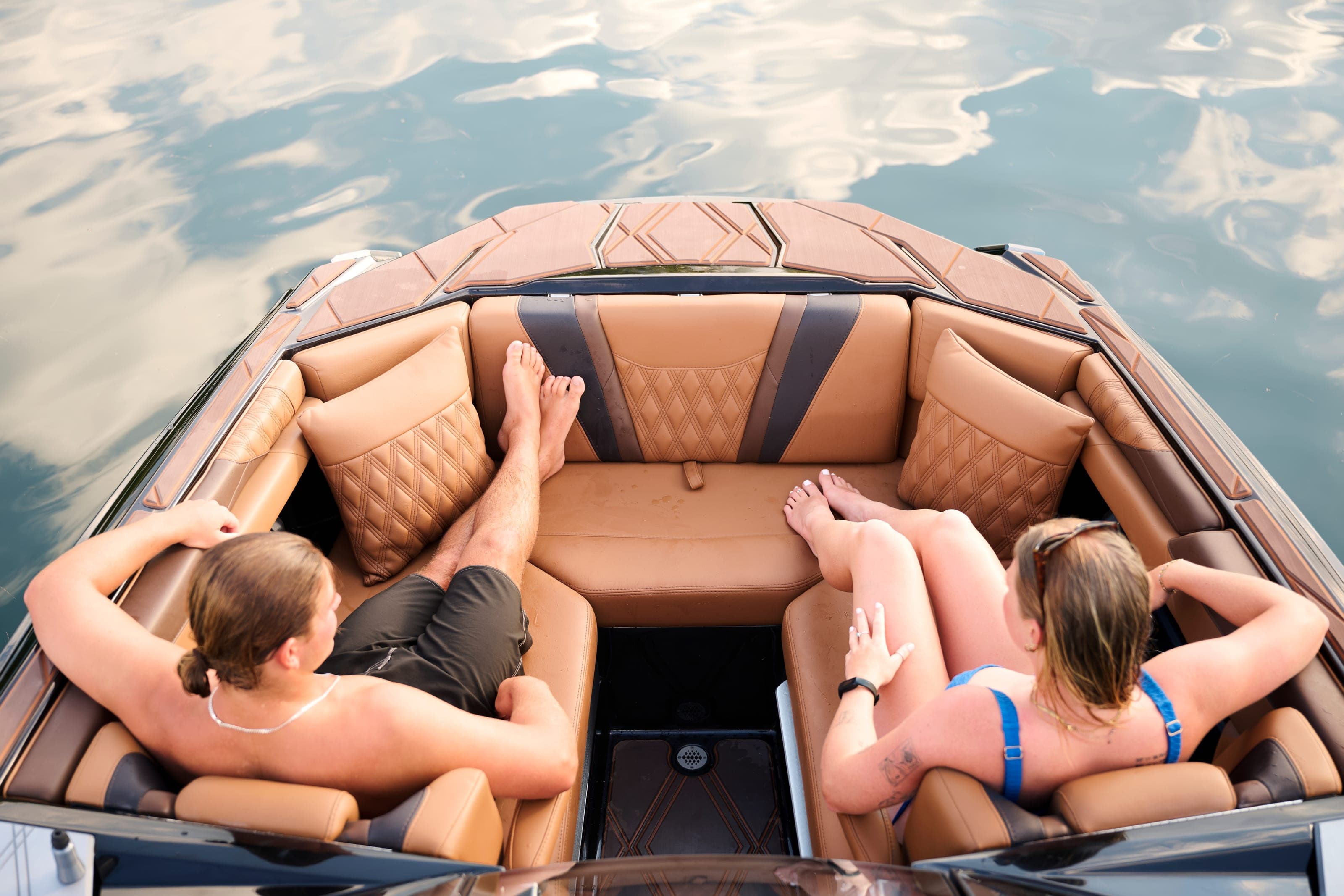 Two people relax in the bow seating of a Malibu M242, seen from above