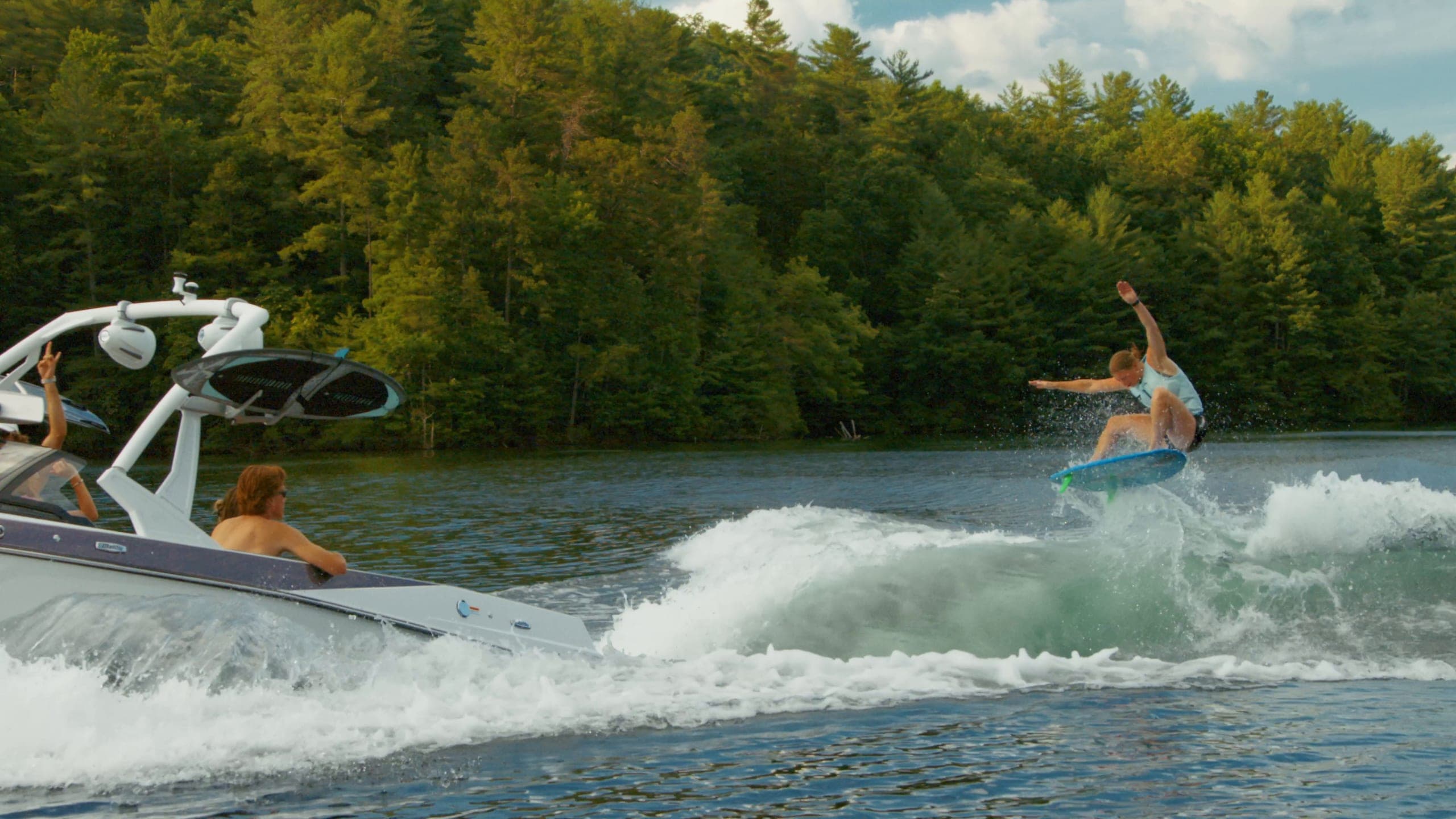 A rider in the air behind a Malibu 20 VTX, then a waterskier in low sun
