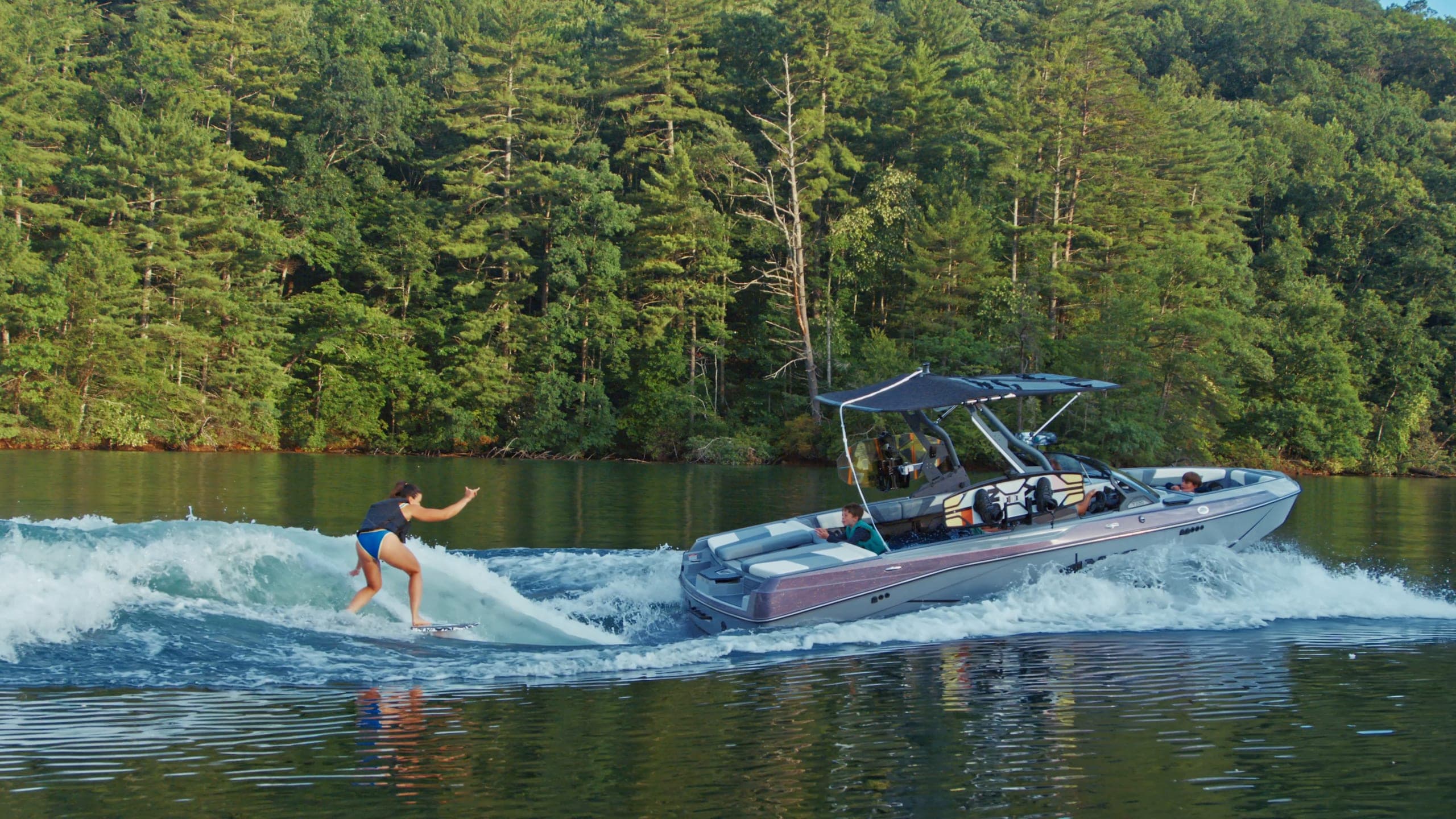 A wakeboarder seen from above, an Axis T220 at speed, a foil rider and a surfer behind the boat