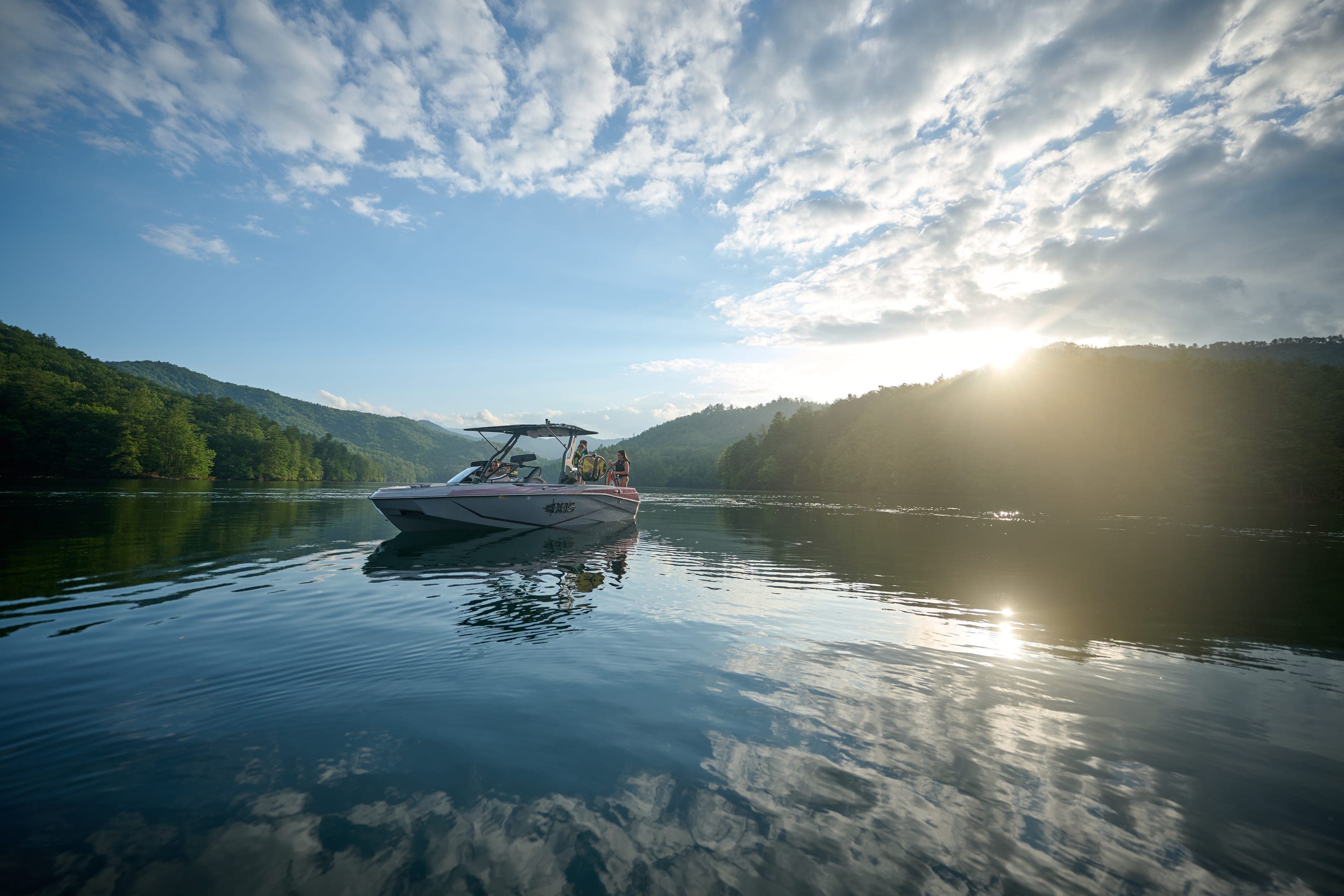An Axis T220 at rest on calm water in the late sun, people aboard