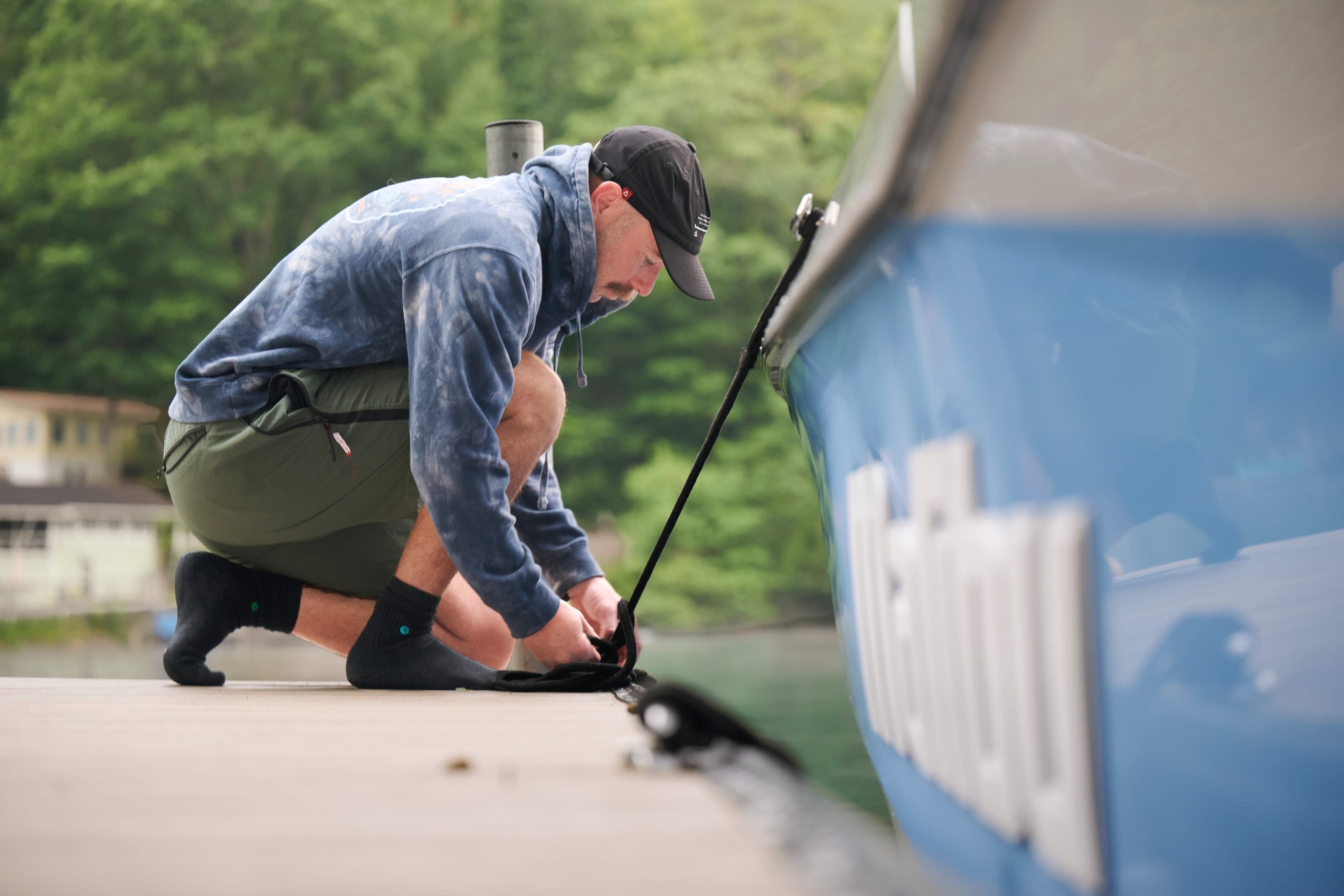 A man kneels on a dock to secure a line to a Malibu 25 LSV